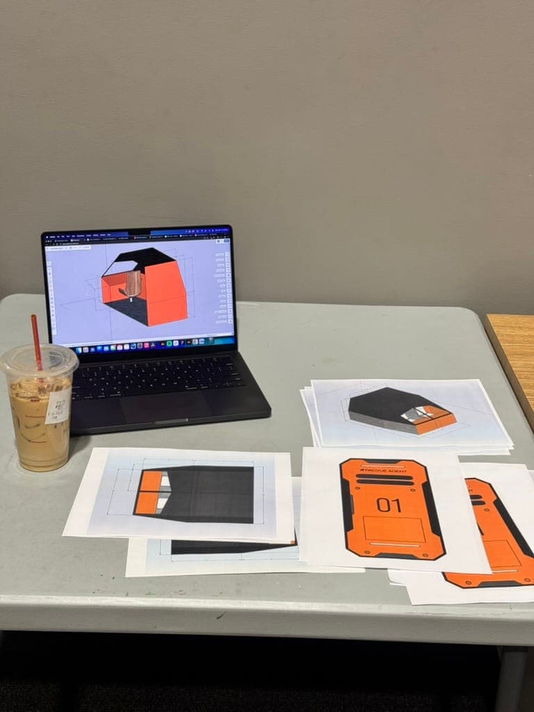 Printed spaceship drawings and a 3D model on a laptop at the production design desk