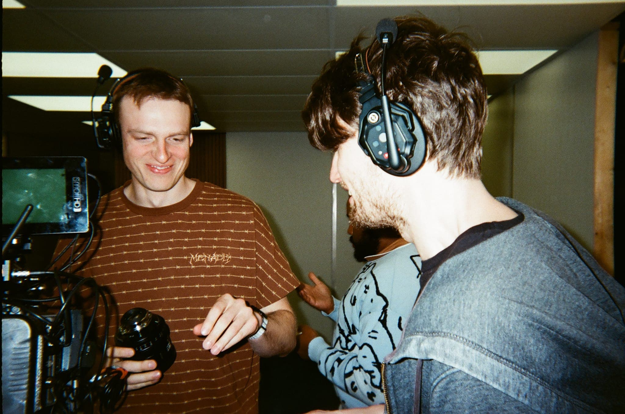 Crew laughing together behind a camera and monitor between takes